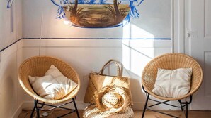 A room with two wicker chairs, a woven basket, and a wall mural depicting a landscape. - Central Studio Suite - Ericeira (Ericeira)