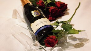 Een fles Riesling Sekt met etiket, een glas en een rode roos.