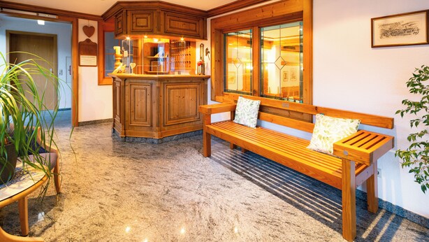 Een gezellig interieur met een houten bank, een keukenhoek en een potplant.