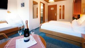Een hotelkamer met twee bedden, een televisie, een fles champagne en een glas op een tafel.