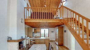 A spacious kitchen with wooden cabinets, a dining table, and a staircase leading to an upper level. - Charming cottage for 6 in Jard-sur-Mer, close to beach and Vélodyssée (Jard-sur-Mer)