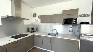 Eine moderne Küche mit grauen Schränken, Edelstahlgeräten, einer Mikrowelle und einer Kaffeemaschine.