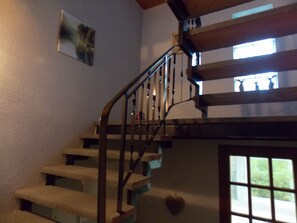 A staircase with a handrail, a picture on the wall, and a window with a view.