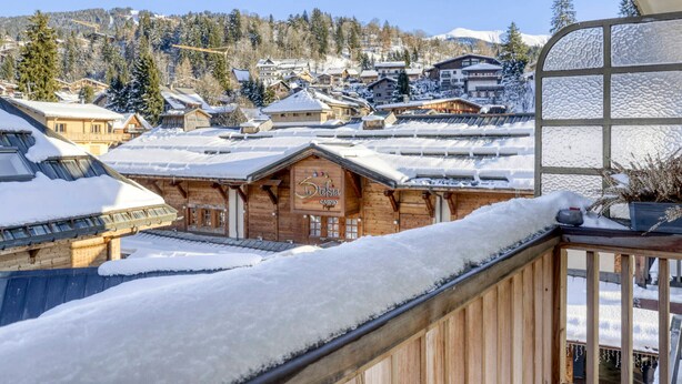 A wooden building with a sign reading "Stella Casino" amidst a snowy village with houses and a mountain in the background. - Central Megève Apartment - 4 Guests - Pets Allowed (Megève)