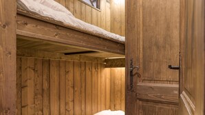 A wooden bunk bed room with a door and a lower bunk bed.