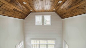 A room with a sloped wooden ceiling, two windows with white frames, and white walls.
