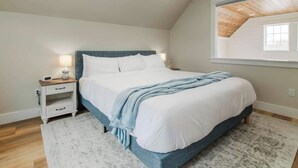 A bedroom with a bed, bedside table, and a window.