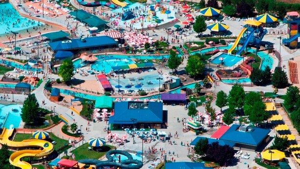 Eine Vogelperspektive eines Themenparks mit mehreren Wasserrutschen, Pools und Picknickbereichen.