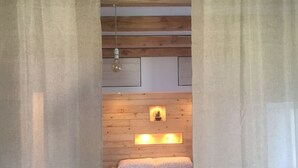 A bedroom with a wooden ceiling, a bed with white bedding and red towels, and a nightstand with a lamp. - ENCHANTING LOFT "Shambalahome.it" (STRESA)