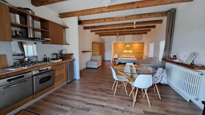 A modern kitchen with wooden cabinets, stainless steel appliances, and a dining area with a glass table and white chairs. - ENCHANTING LOFT "Shambalahome.it" (STRESA)