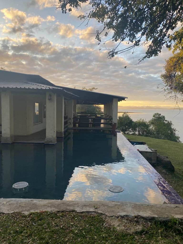 Una casa con piscina, terraza techada y vista al agua.