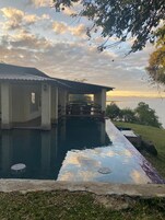 Una casa con piscina, terraza techada y vista al agua.