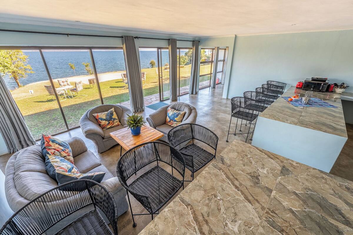 A spacious balcony with a view of the sea, furnished with a sofa, chairs, and a table.