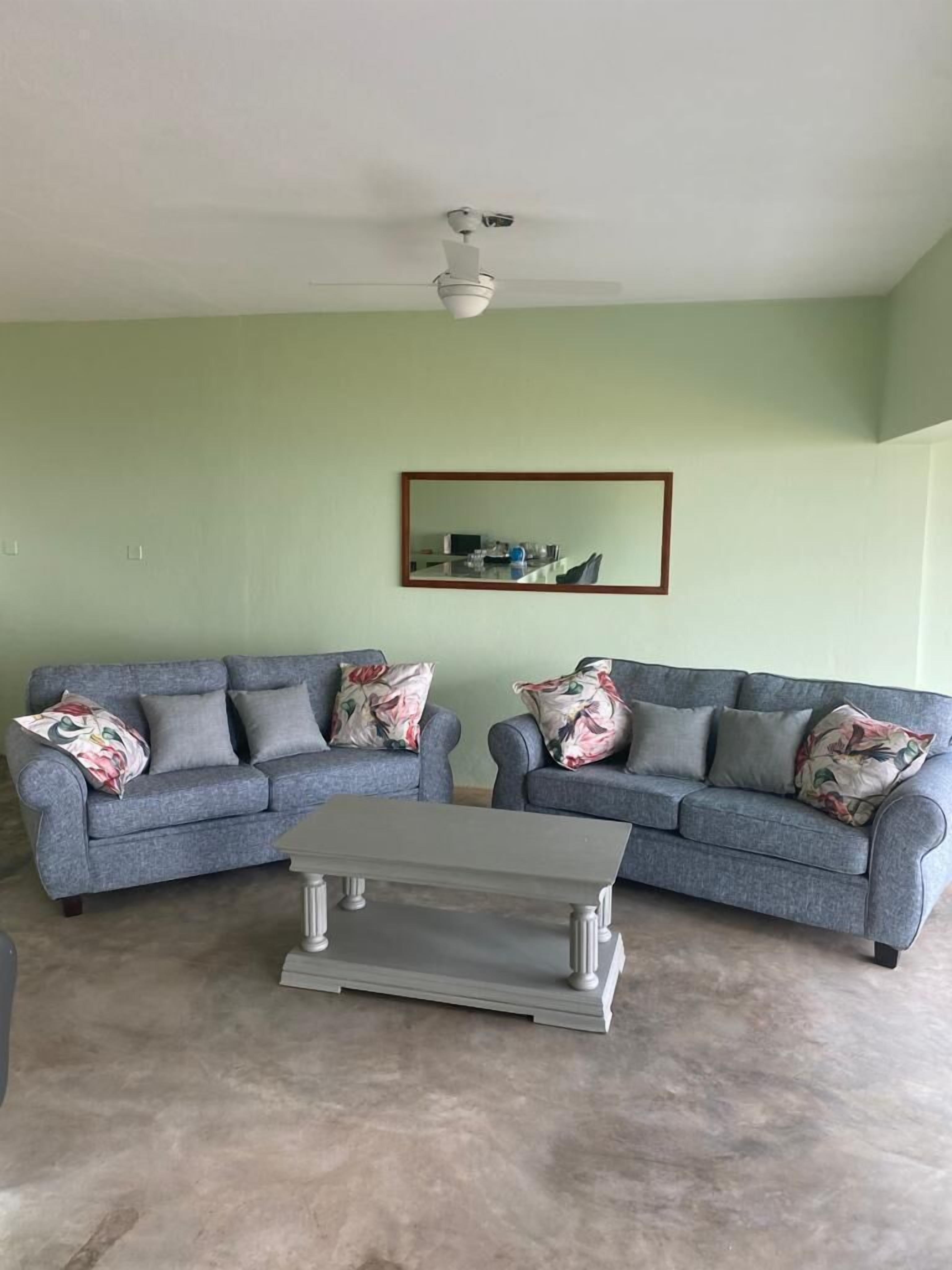 A living room with two grey sofas, a coffee table, and a ceiling fan.