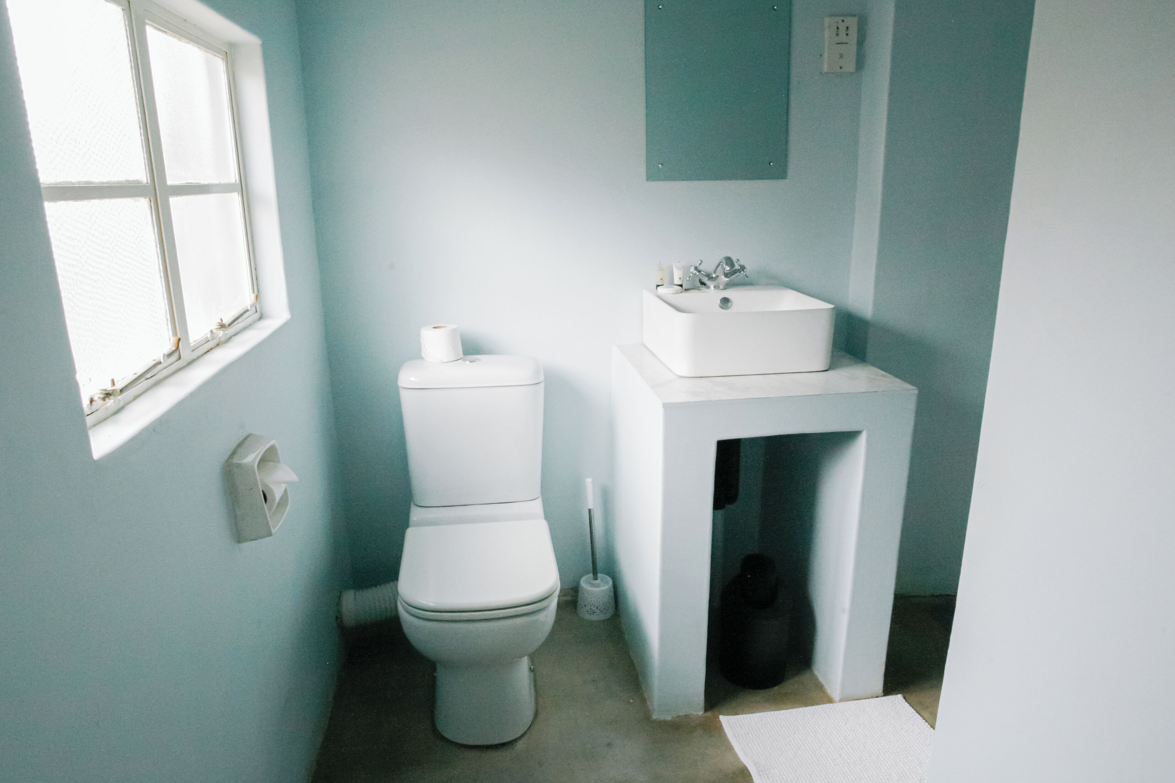 Un baño con inodoro, lavabo y ventana.