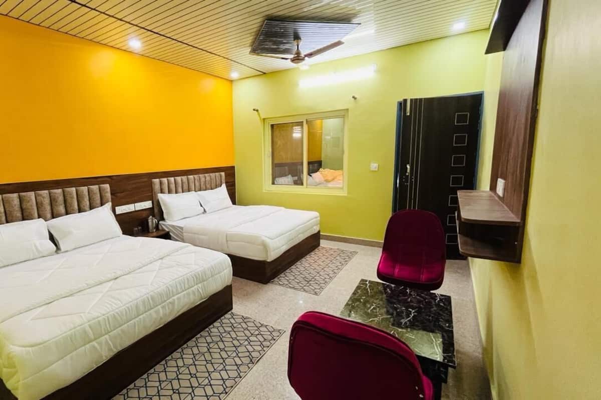 A hotel room with two beds, a desk, a chair, a window, and a door.