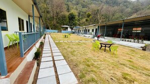 A hotel with a covered outdoor area, a pathway, and outdoor seating. - Glorious Resort Rishikesh (Rishikesh)