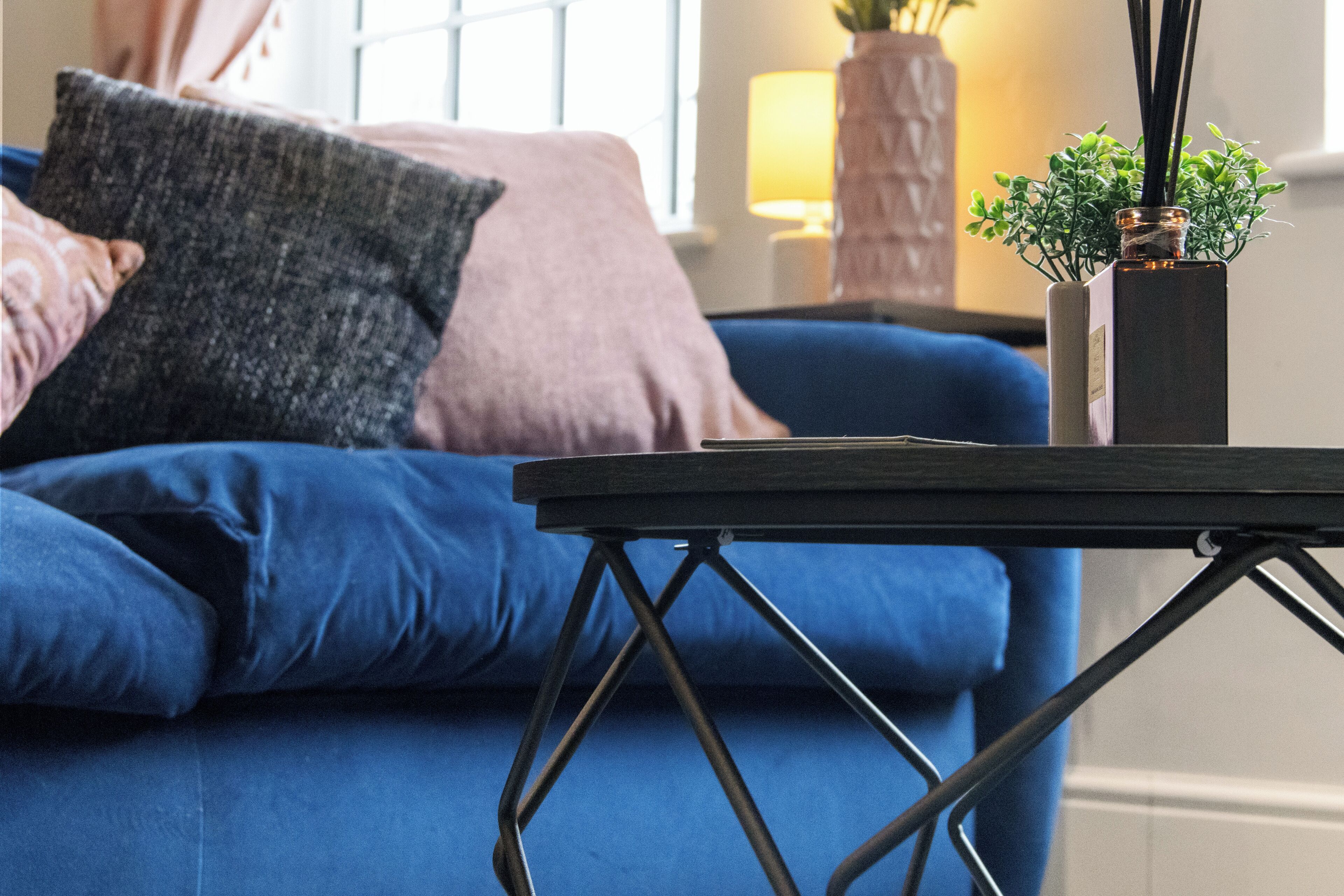 Un sofá azul con una mesa de centro oscura.