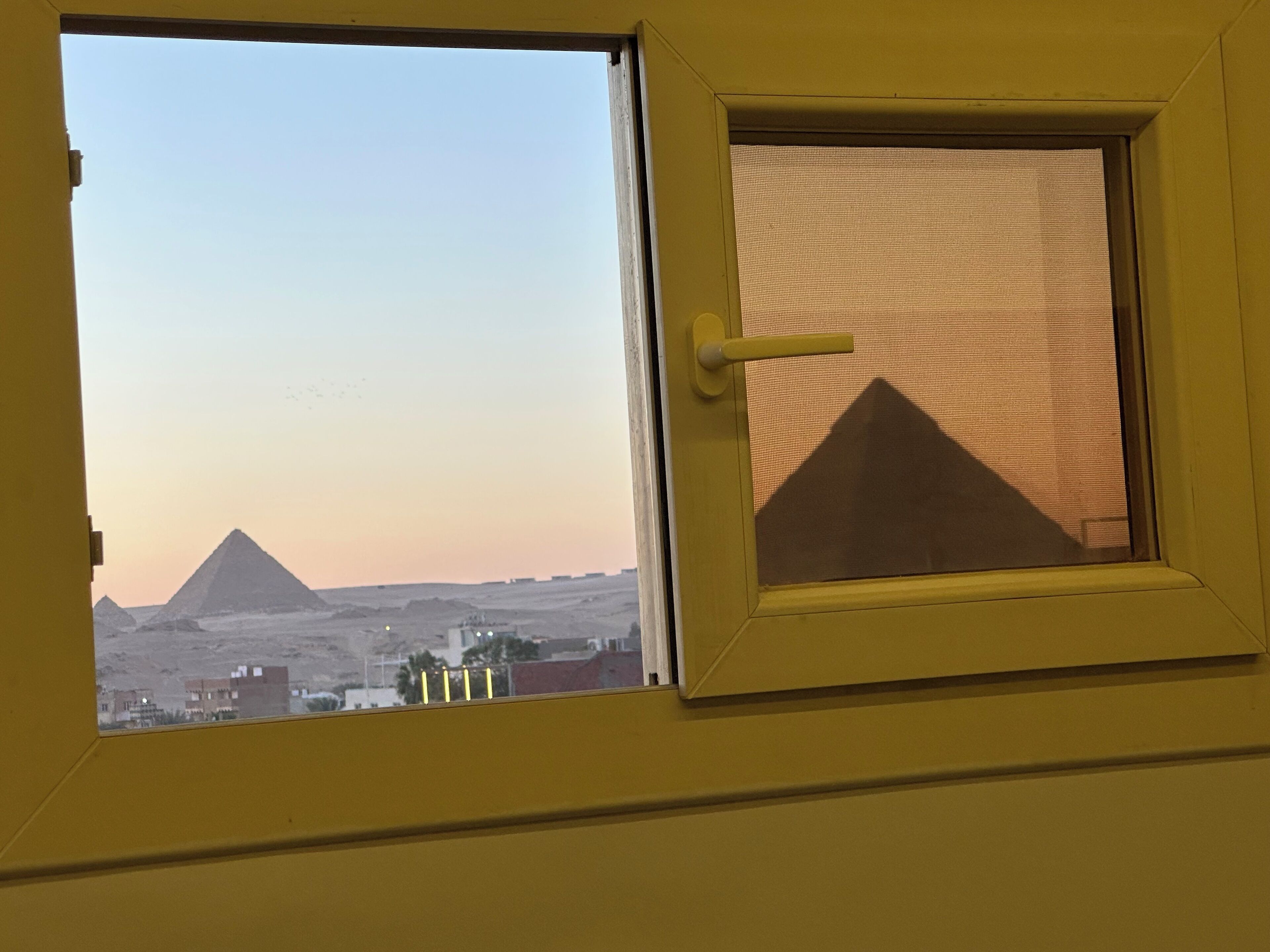 Una ventana con vista a una pirámide y edificios.