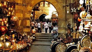 A market with various stalls selling traditional items, including metalware and textiles, under an archway. - Hapi Pyramids Hotel  (Giza)