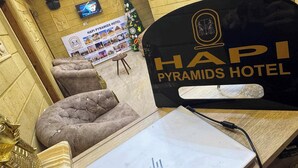 A reception area of Hapi Pyramids Hotel with a reception desk, plush seating, a Christmas tree, and a poster advertising the hotel. - Hapi Pyramids Hotel  (Giza)