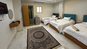 A hotel room with two beds, a small desk, a television, and a mirror. - Hapi Pyramids Hotel  (Giza)