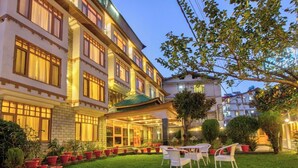 A hotel with a well-lit outdoor seating area, a covered entrance, and a garden with potted plants. - Hayer Regency (Manali)