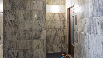 An elevator with marble walls and a control panel.
