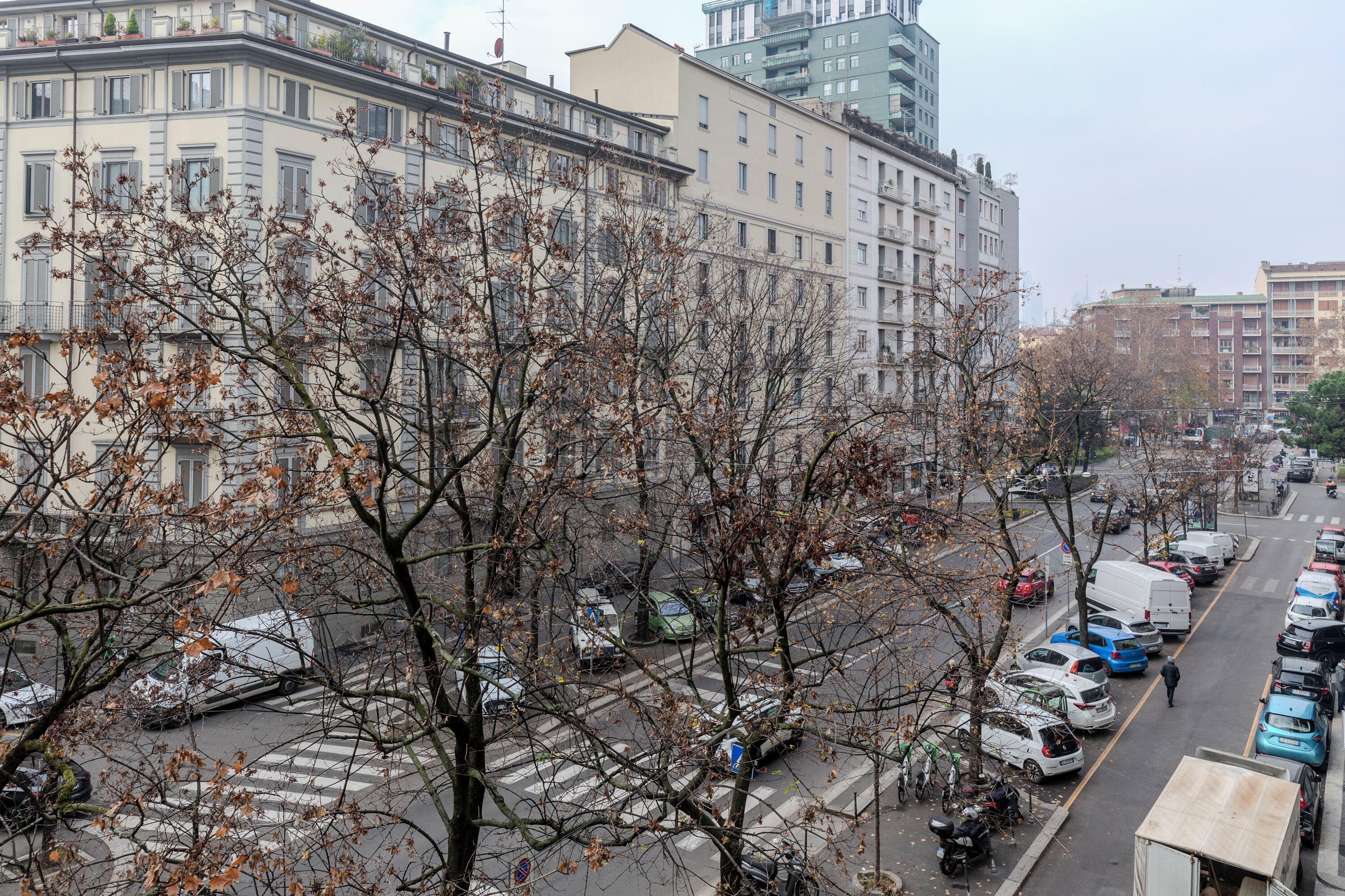 Una calle urbana con coches estacionados y edificios al fondo.