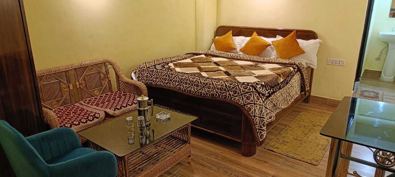 A room with a bed, a sofa, a table, and a glass table.
