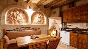 A rustic kitchen with a stone fireplace, wooden furniture, and a stone wall with carvings. - Avanos Evi (Avanos)