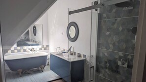 Un baño moderno con una bañera independiente, un lavamanos y una ducha con mampara de vidrio.