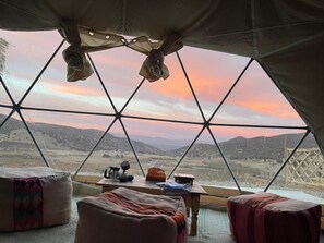 Una stanza a cupola geodetica con un tavolo, sedie e vista su un paesaggio montuoso.