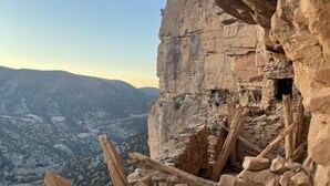 A rocky cliff with a small cave entrance and scattered wooden debris. - Eagles dôme (Boutferda)