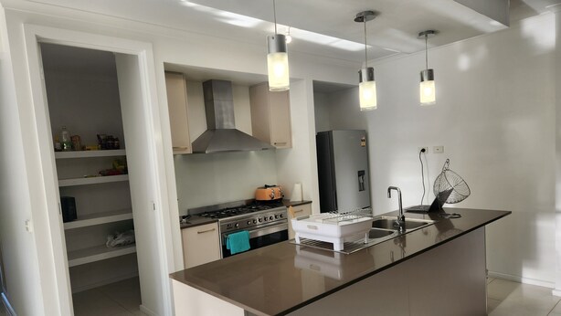 A modern kitchen with a central island, stainless steel appliances, and pendant lighting. - Tranquil in Alfredton (Alfredton)