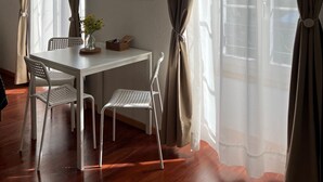A room with a dining table, chairs, a small plant, and curtains. - Nimbuzzz Apartments (Unterseen)