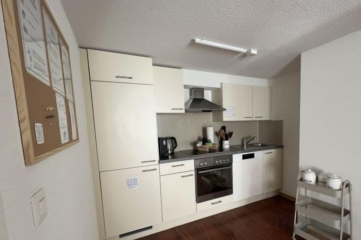 Une cuisine de taille réduite avec des meubles blancs, une cuisinière et un évier.