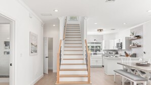A modern kitchen with white cabinetry, a central island, and a dining area with a bench.