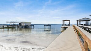 A wooden pier leading to a small house with a dock extending into calm water.