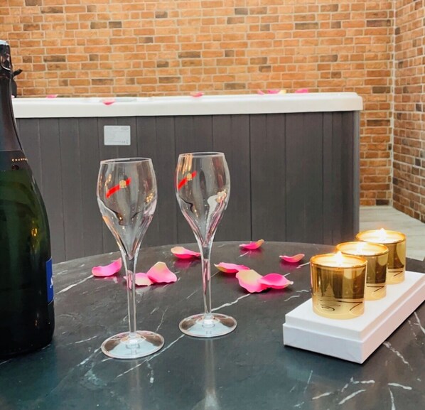 Une table sur laquelle se trouvent deux verres à vin, une bouteille de champagne et trois bougies allumées, le tout posé sur une surface en marbre.