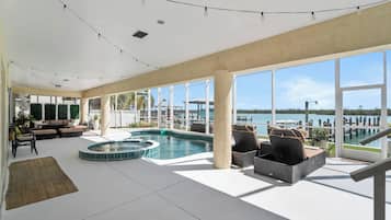 Amplio espacio interior con piscina, asientos y ventanas grandes que ofrecen vista al agua.