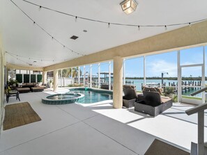 A spacious indoor area with a pool, seating, and large windows offering a view of the water.