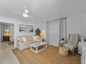 A living room with a ceiling fan, a sofa, a coffee table, a chair, and a lamp.