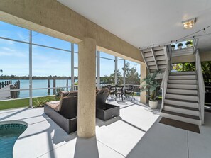 Un amplio espacio al aire libre con piscina, asientos y vistas al agua.