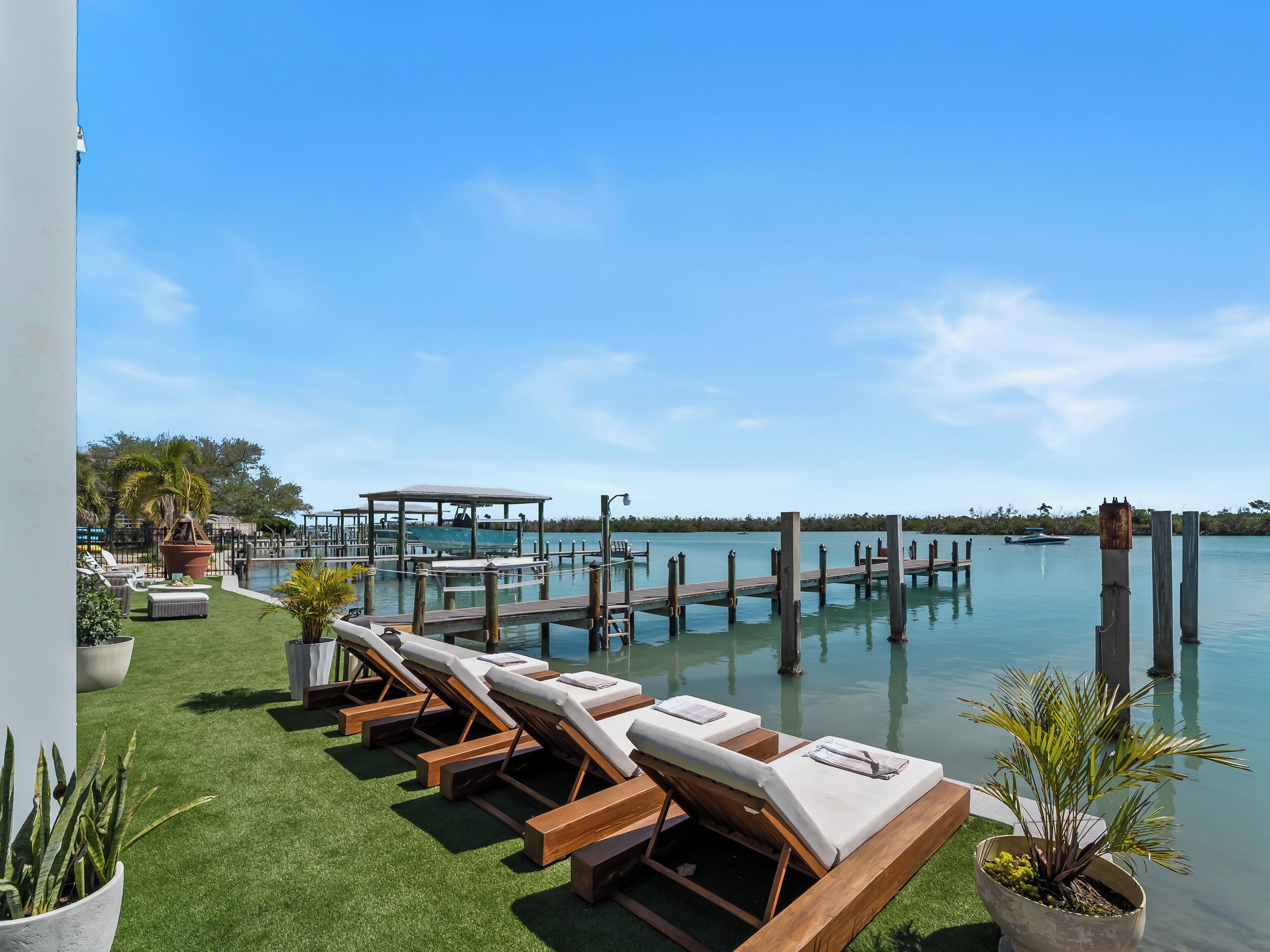 A poolside area with lounge chairs, a wooden deck, and a view of the water.