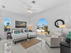 A hotel room with two beds, a ceiling fan, a large window with a view, a round mirror, and a side table with a lamp. - Bayfront Home - Pool Dock 3/3 with Studio (Englewood)