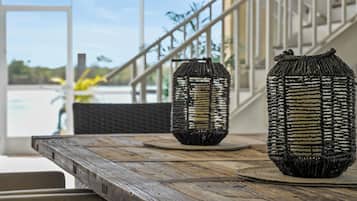 Una mesa de madera con faroles trenzados y vistas a una escalera y un espacio exterior.