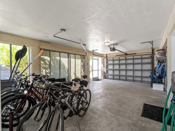 A garage with bicycles parked inside, a concrete floor, and a garage door.