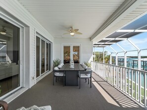 A covered outdoor area with a table and chairs, a ceiling fan, and a view of the water.