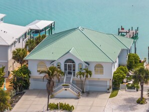 A two-story house with a green roof, a front porch, and a staircase leading to the entrance. - Bayfront Home - Pool Dock 3/3 with Studio (Englewood)